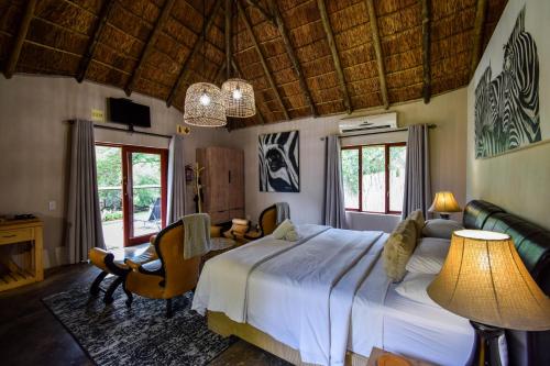 a bedroom with a bed and a table and a chair at Mologa River Lodge in Rust de Winter
