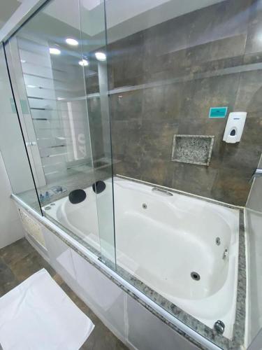 a bathroom with a bath tub with a glass enclosure at AJ TERMAS HOTEL IRAÍ in Iraí
