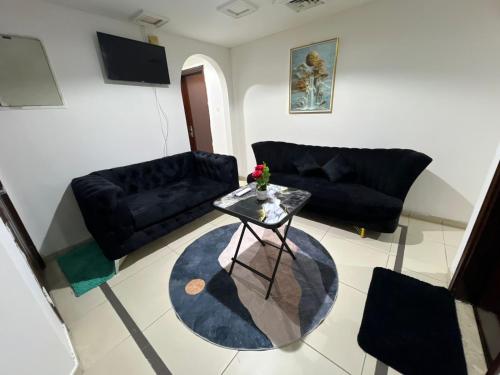 a living room with black couches and a table at ALEX Hostel C2602 - Bed in Shared Room for Males in Sharjah