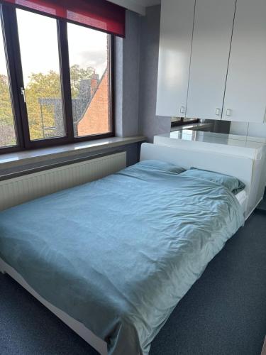 a bed in a room with two windows at Antwerp West Side Penthouse in 't Hoeksken