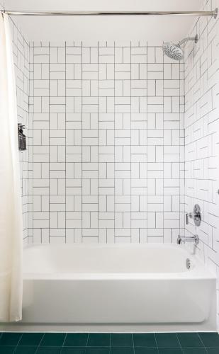 a white bath tub in a white tiled bathroom at Trailhead Lodge in Estes Park