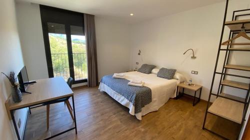 a bedroom with a bed and a desk and a window at Hostal Restaurant Mussons Vins in Poboleda