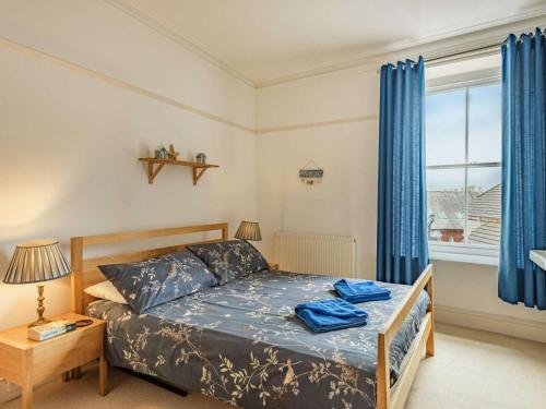 a bedroom with a bed and a window with blue curtains at 5 Bed in Swanage oc-dc060 in Swanage