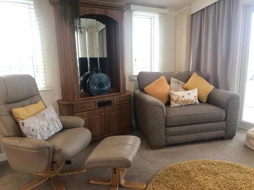 a living room with a chair and a couch and a mirror at 29 The Beeches in Gilcrux