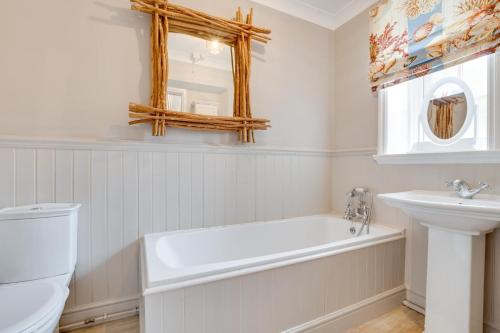a white bathroom with a tub and a sink at 4 Bed in Bamburgh oc-gd1264 in Bamburgh