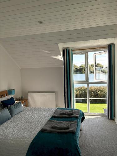 a bedroom with a bed and a large window at Lakefront Lodge w SUP & Fishing Access Cotswolds in Gloucestershire
