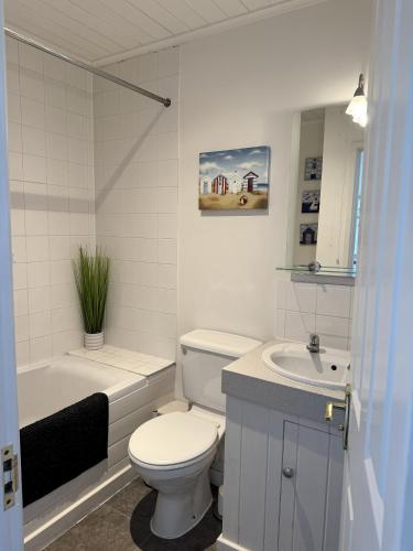 a white bathroom with a toilet and a sink at Lakefront Lodge w SUP & Fishing Access Cotswolds in Gloucestershire