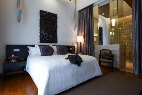 a bedroom with a large white bed and a chair at The Lake Garden Hotel Nay Pyi Taw - MGallery Collection in Nay Pyi Taw