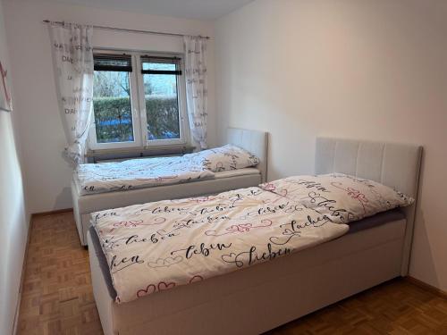 two twin beds in a room with a window at Wagner Apartment Bayreuth FeWo - Erdgeschoss - nähe Festspielhaus - Free-WiFi - Schlafzimmer - Boxspringbetten - große Küche - Dusche - Badewanne - extra WC - Terrasse - DTV-Zertifiziert in Bayreuth