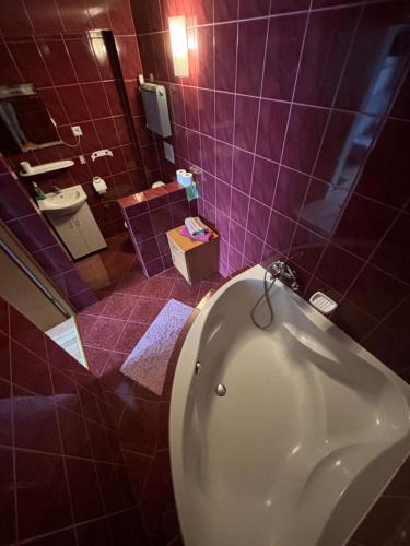 a bathroom with a white tub and purple tiles at Abba -pokoje wakacyjne in Wisła