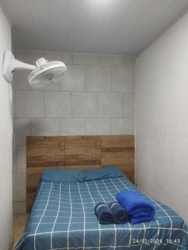 a bedroom with a bed with blue sheets and a light at Suíte 2 Itaguaí in Itaguaí