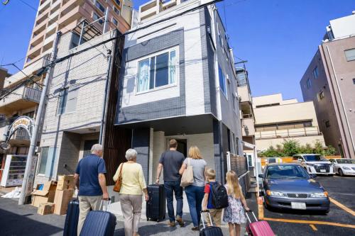 a group of people walking down a street with luggage at Free parking for compact cars 4 minutes walk from Kawaguchi Newly built three-story single-family house with 78 square meters 18 minutes by train to Ueno in Kawaguchi