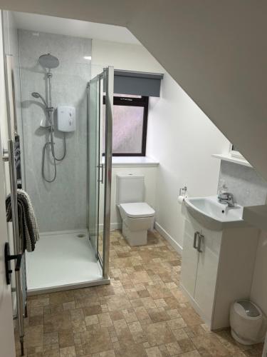 a bathroom with a shower and a toilet and a sink at Mortlach Cottage in Dufftown