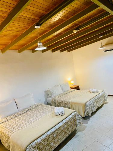two beds in a room with wooden ceilings at BUENAVISTA INN in Maiquetía