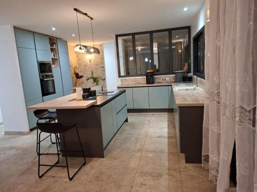 Una cocina con gabinetes azules y una isla con encimera. en Chez moi, en Gan