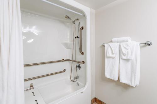 a bathroom with a shower and white towels at Mon Joli Motel in Sainte-Flavie