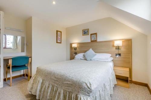 a bedroom with a large bed and a blue chair at 2 Bed in Smallburgh oc-h33734 in Dilham