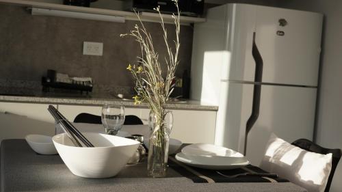 a kitchen table with a vase of flowers and a glass at Ecos de Mar Refugios in Puerto Pirámides