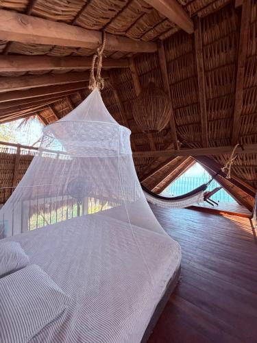 ein Bett in einer Strohhütte mit einem Moskitonetz in der Unterkunft Casa Guií in Arroyo Cruz