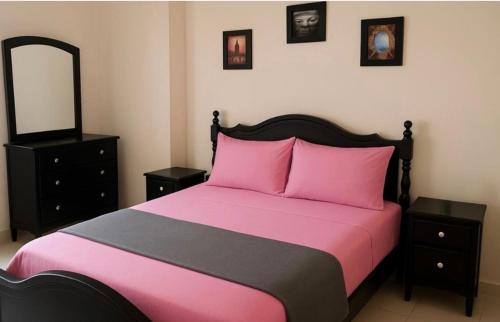 a bedroom with a bed with pink sheets and a mirror at Suite Home martil in Martil