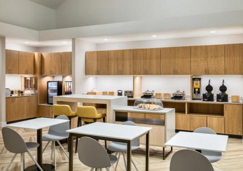 a kitchen with tables and chairs and a counter at TownePlace Suites by Marriott Charlotte LoSo Airport in Charlotte
