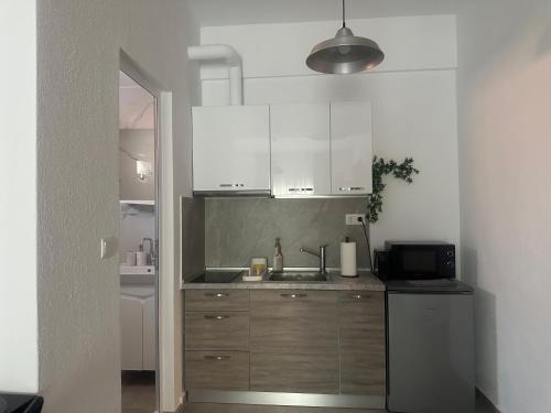 a kitchen with white cabinets and a sink at AsproLux Seaside Studios in Asprovalta