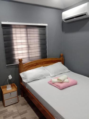 a bedroom with a bed with a pink towel on it at Caperina del Casa-Rental in Naic