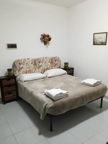a bed with a floral headboard and two towels on it at Salina in Trappeto