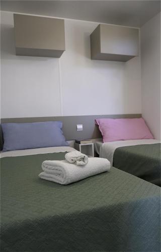 a room with two beds with towels on them at Villaggio Camping Torre Del Porticciolo in Porto Conte