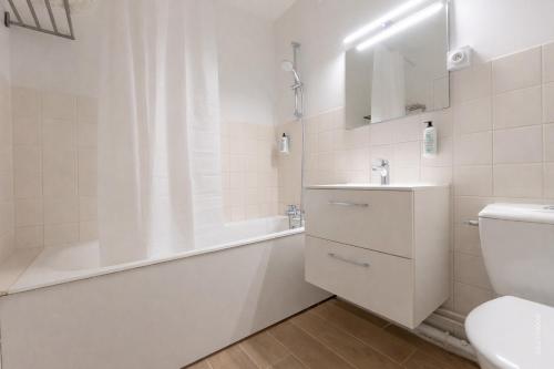 a white bathroom with a tub and a sink and a toilet at Le Kuku Beach - Appartement de charme à Digoin in Digoin