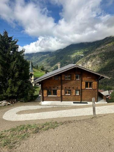 a large wooden house with a mountain in the background at Swiss Chalet - upstairs apartment in Grengiols