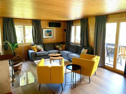 a living room with a couch and yellow chairs at Swiss Chalet - upstairs apartment in Grengiols
