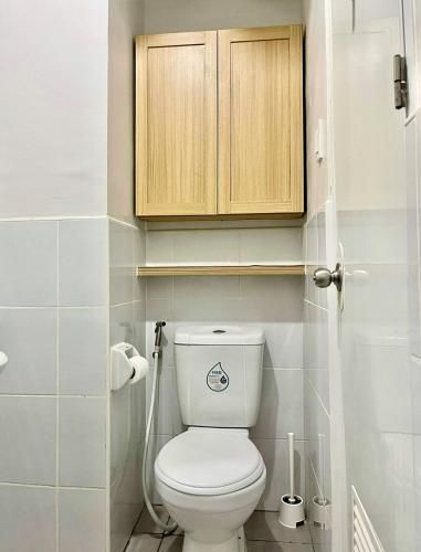 a bathroom with a toilet with a wooden cabinet at Suite Talie Cebu Cozy Modern Stay with Pool & Netflix in Lapu Lapu City