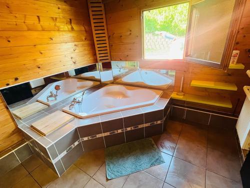 a large bathroom with a tub and a window at Cozy chalet with Nordic bath in Plancher-Bas