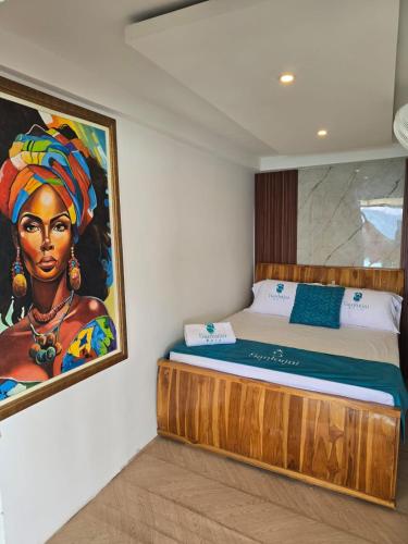 a bed in a room with a painting on the wall at Santorini Barú in Playa Blanca