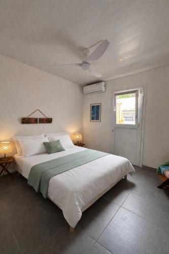a bedroom with a large white bed and a window at Les bonites carbet pieds dans l eau in Le Carbet