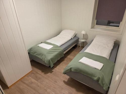 two twin beds in a small room with a window at The Old Printing House H0101 - 4 bedroom apartment in Tromsø