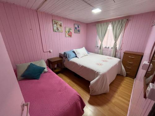 a bedroom with two beds in a pink room at Cabaña Terraza Choshuenco in Panguipulli