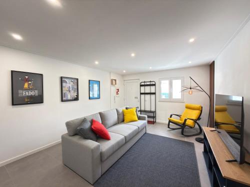 a living room with a gray couch and yellow pillows at Alma do Tejo - Alma Nossa in Montijo