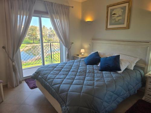 a bedroom with a bed with blue pillows and a balcony at Beautiful Villa on Boavista Golf Resort - Daily Service & Spa Access in Lagos