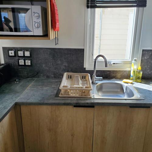 a kitchen sink with a dish drying rack next to it at Vacances la Palmyre in Les Mathes