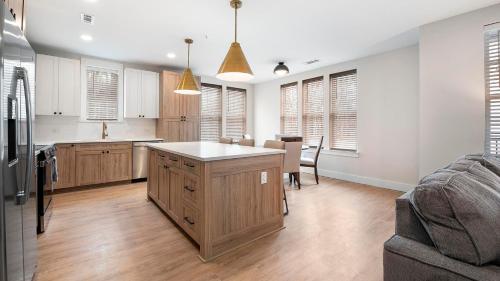 a kitchen with white walls and wooden cabinets at Landing Modern 2BD Gym Pool in Cornelius