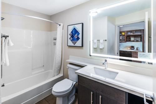 a bathroom with a sink and a toilet and a tub at Candlewood Suites - Topeka West by IHG in Topeka