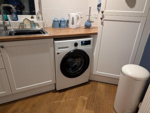a kitchen with a washing machine and a sink at Extended Fishermans cottage with stunning sea views in The Mumbles