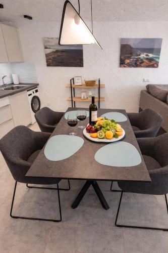 a table with a plate of fruit and wine glasses at Villa Sotavento Modern new apartment in Park Natural Adults Only in Playa Jandia