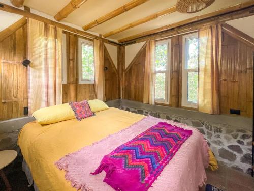 una camera da letto con un letto grande in una stanza con finestre di Casa Oak a Tzununá