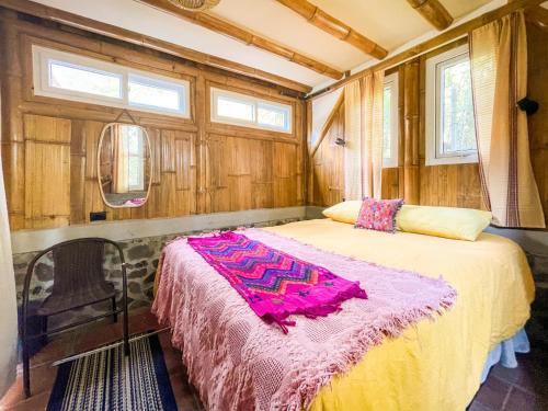 una camera da letto con un letto con una coperta rosa sopra di Casa Oak a Tzununá