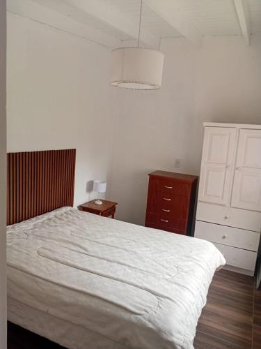 a bedroom with a white bed and a dresser at Departamentos Ruca Lauquén in Necochea