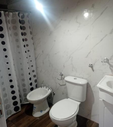 a white bathroom with a toilet and a sink at Departamentos Ruca Lauquén in Necochea