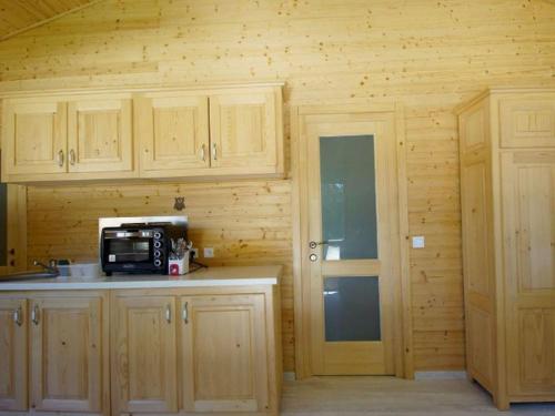 a kitchen with wooden cabinets and a microwave at Charmante Cabane 5 Pers, Chauffée - API-1-52-1704 in Champvert